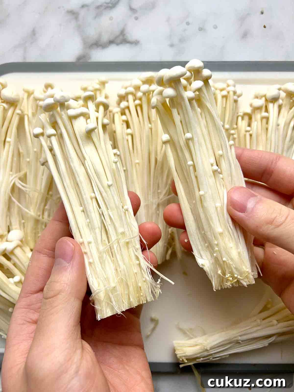 holding two chunks of enoki