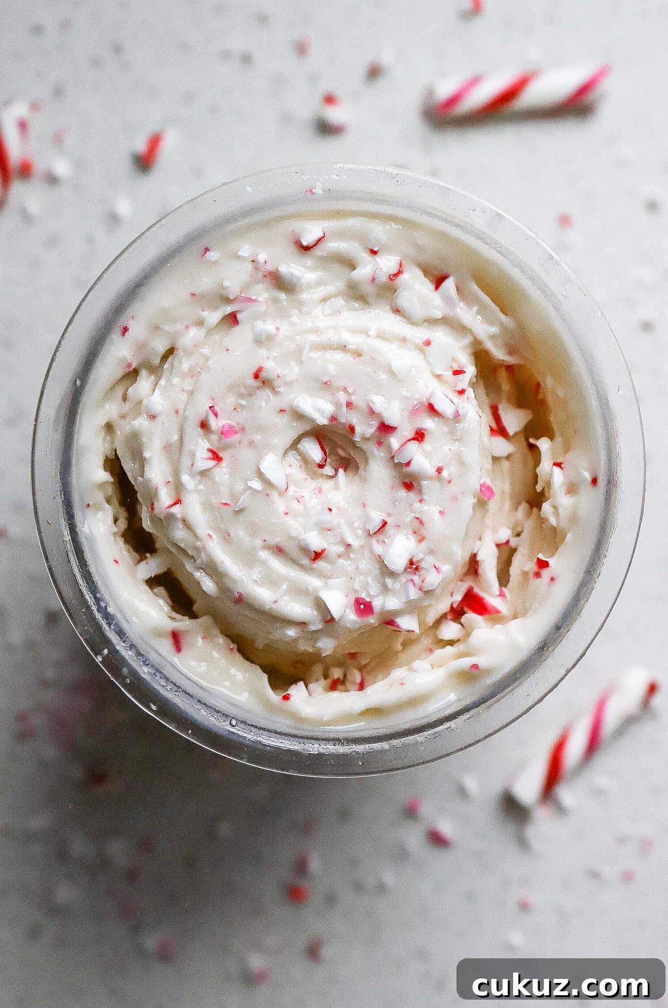 Top down view of protein peppermint ice cream in a ninja creami pint container with crushed candy cane pieces on top.