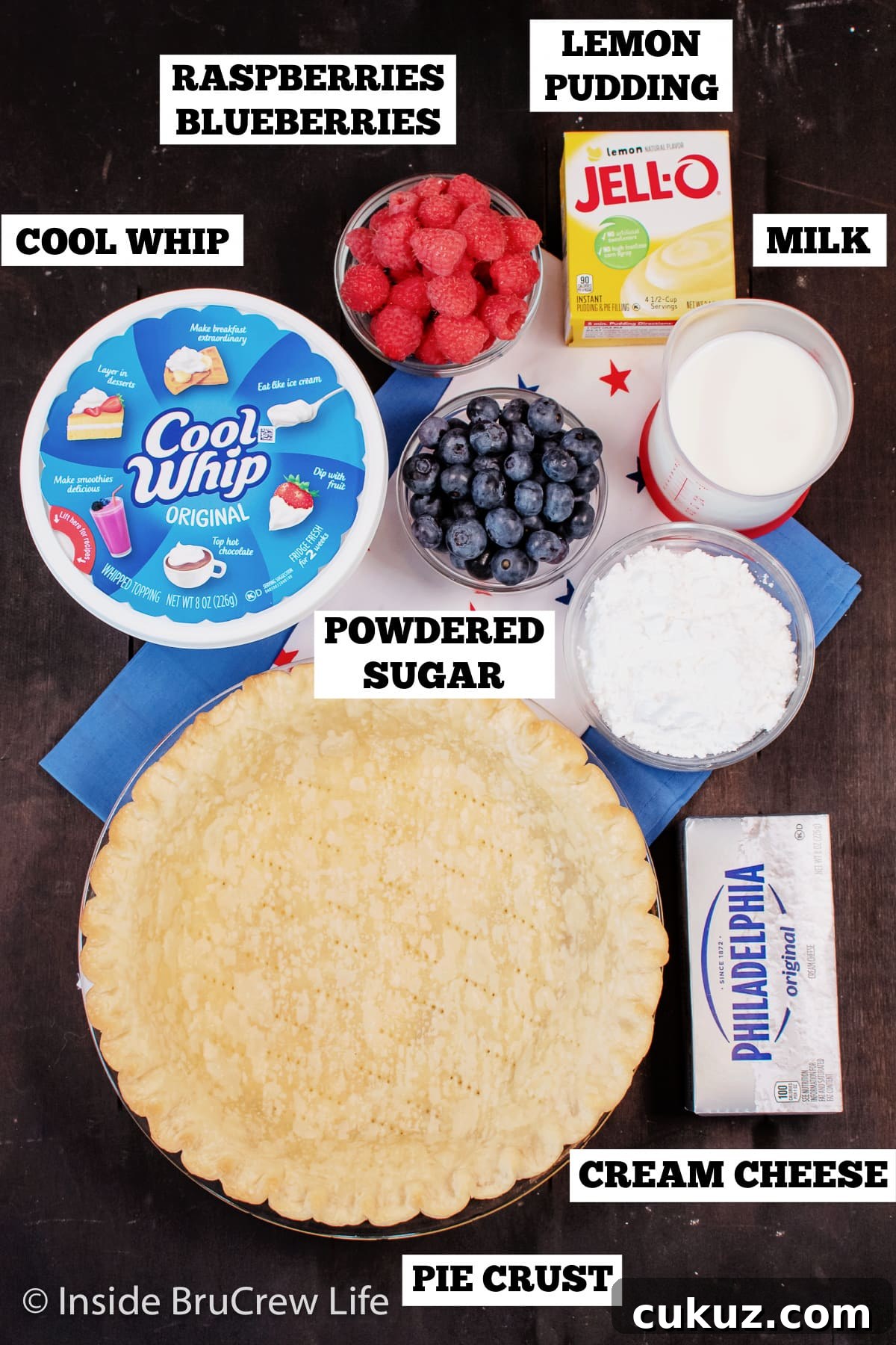 A brown board with bowls of ingredients needed to make a cream cheese pie.