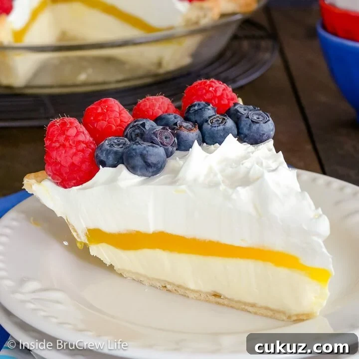 A slice of lemon pie topped with berries on a white plate.