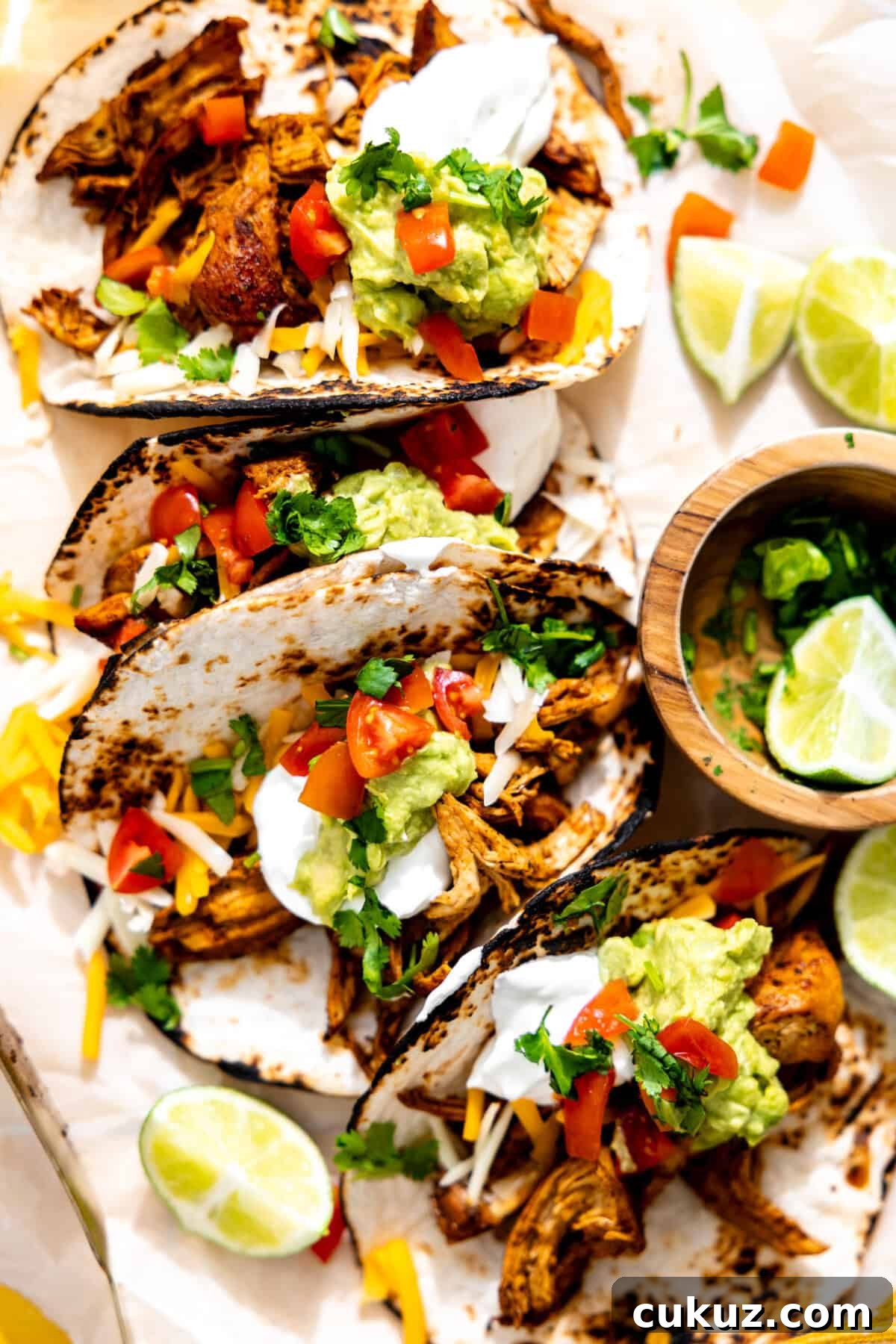 Chicken tacos topped with sour cream, guacamole and diced tomatoes. 