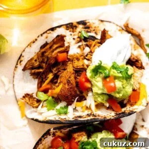 Chicken tacos served with sour cream, guacamole, and diced tomatoes.