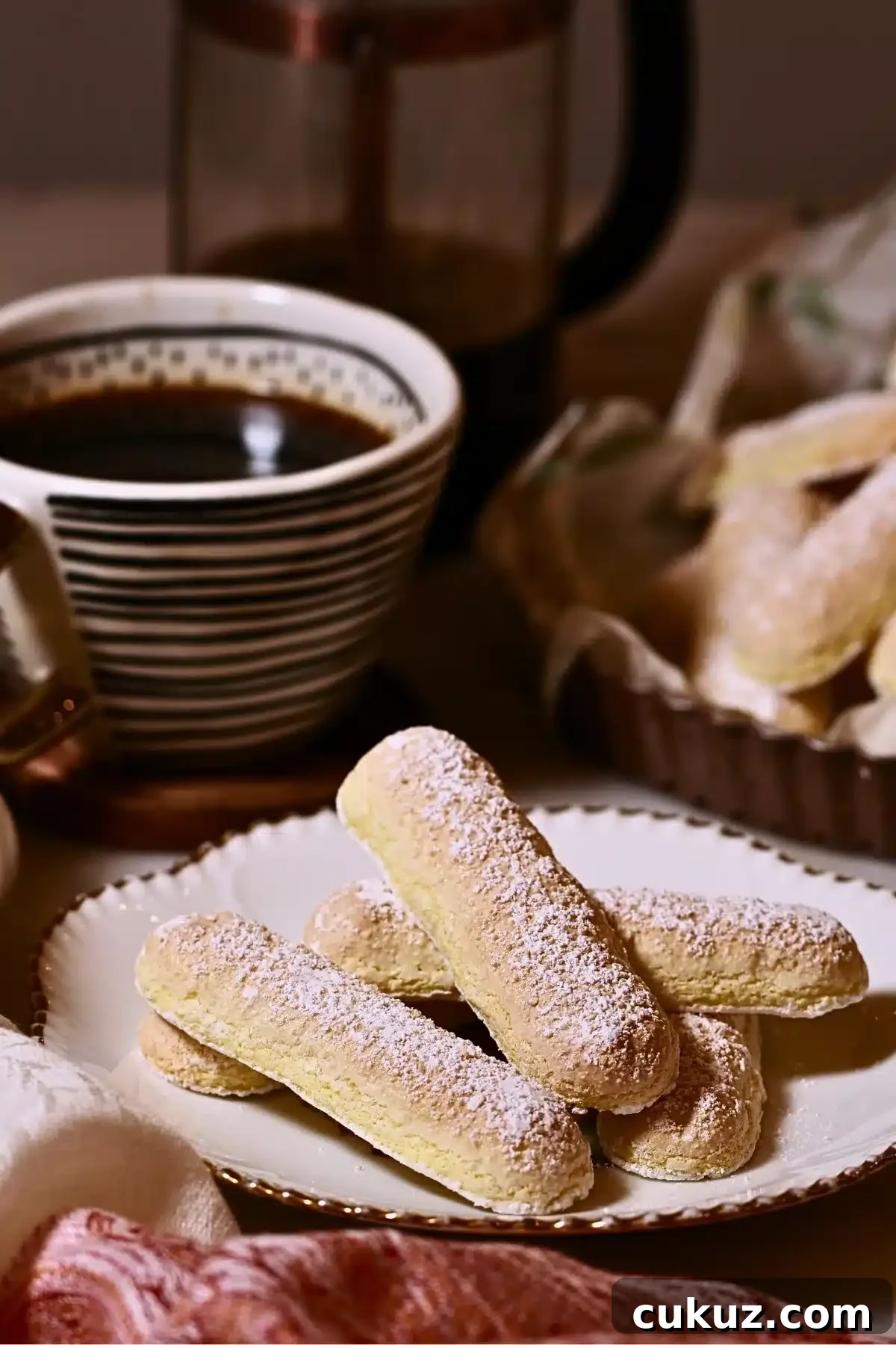 ladyfingers on a plate with a cup of coffee behind