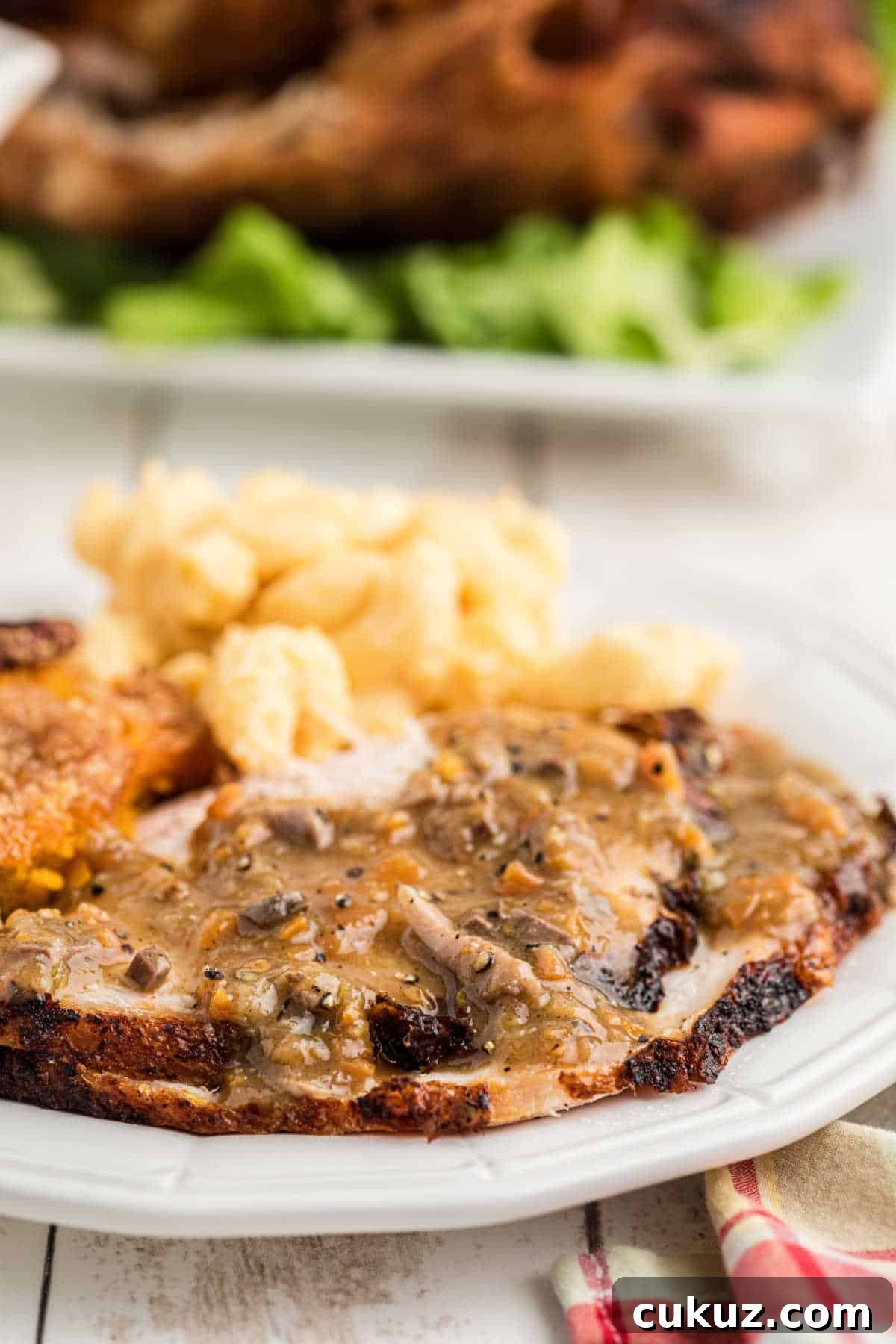 Close up side show of a plate of sliced turkey and sides with a giblet gravy poured on top.