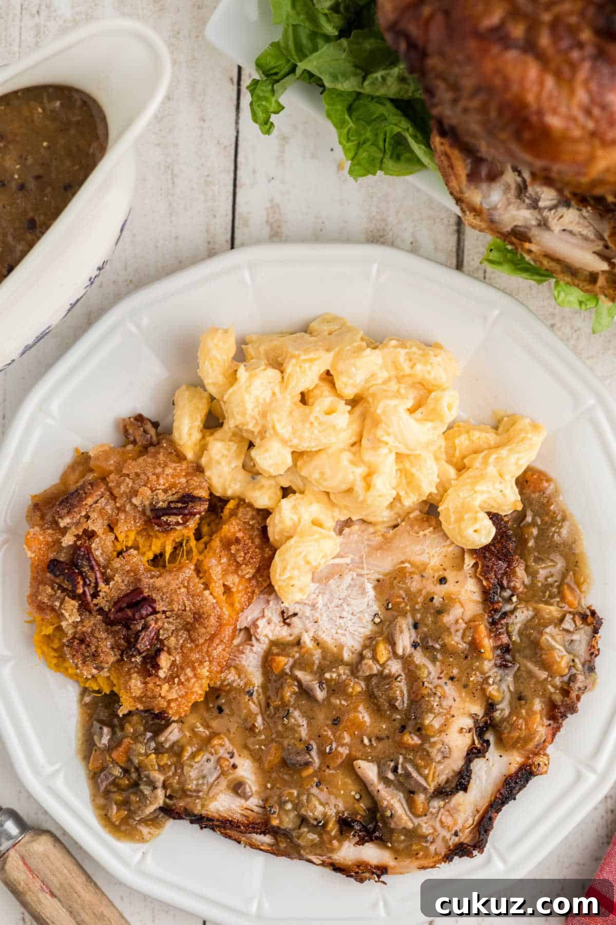 A delicious looking plate with turkey, mac and cheese and sweet potato casserole with giblet gravy poured over the turkey.