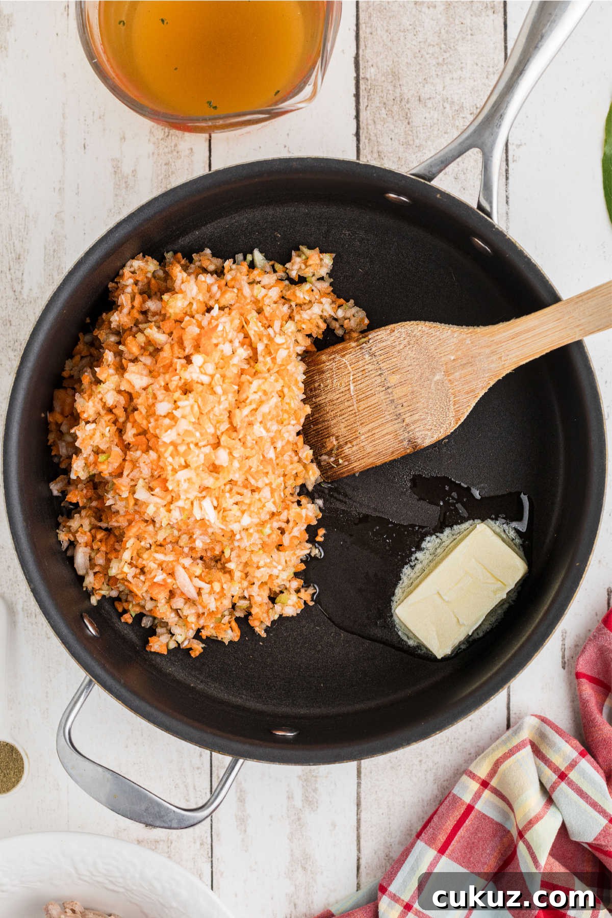 A large skillet with finely diced vegetables and butter.