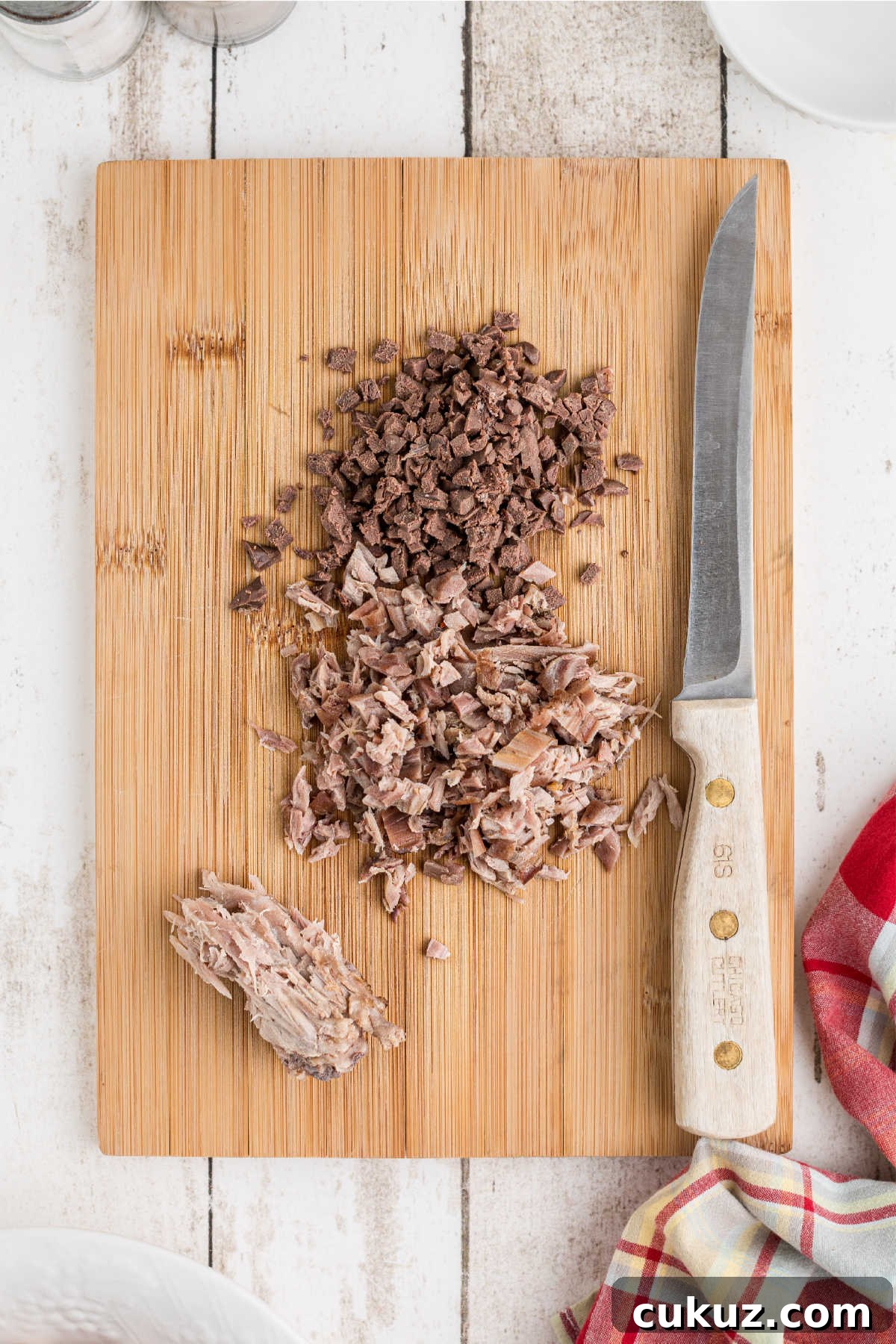 Meat removed from bone and finely diced, on a chopping board.