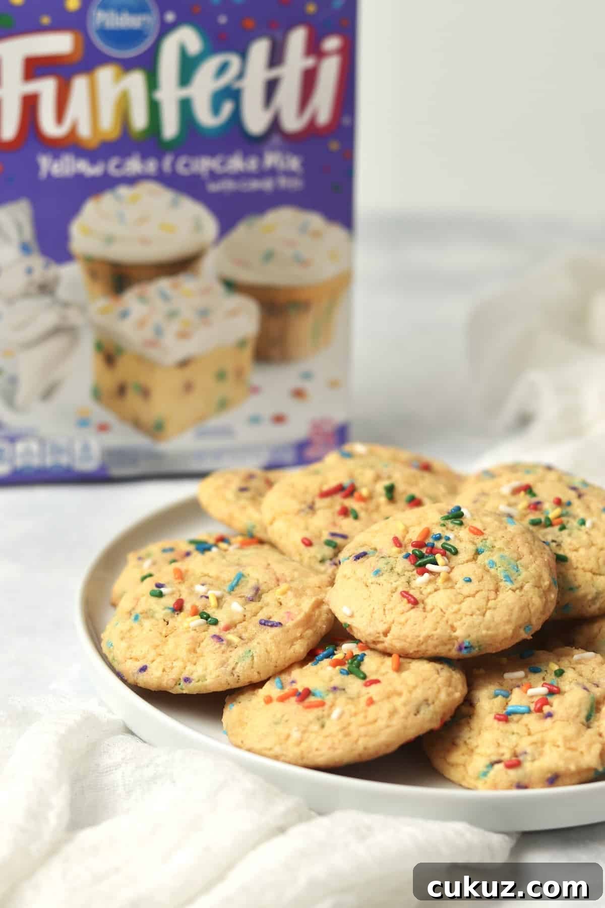 3-Ingredient Funfetti Cake Mix Cookies Recipe 2 Plate of funfetti cookies with a box of funfetti cake mix in background.