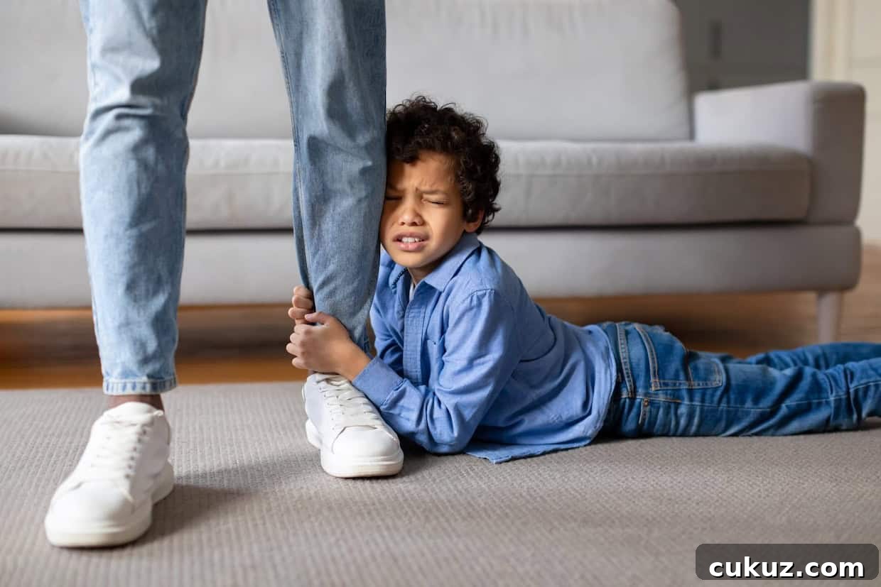 A child lying on the floor grips an adult's leg tightly with a distressed expression.