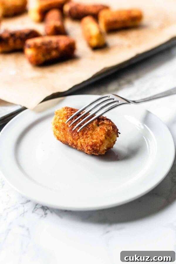 Homemade potato croquette on a white plate with a fork. Looks very tasty.