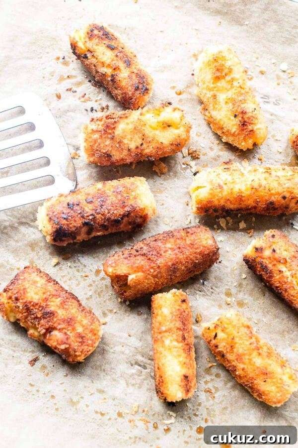 Crispy potato croquettes on a baking sheet. You can make the croquettes in an oven or fry them in a skillet.