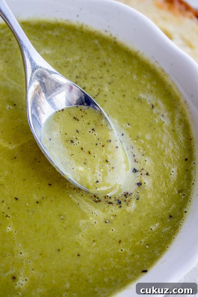 Creamy Frozen Pea Soup Ready in 30 Minutes 4 a spoon dipping into homemade pea soup.