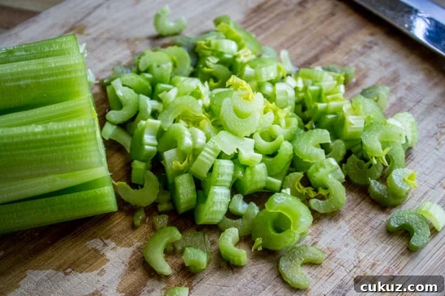Creamy Frozen Pea Soup Ready in 30 Minutes 5 chopping celery on a wooden cutting board.