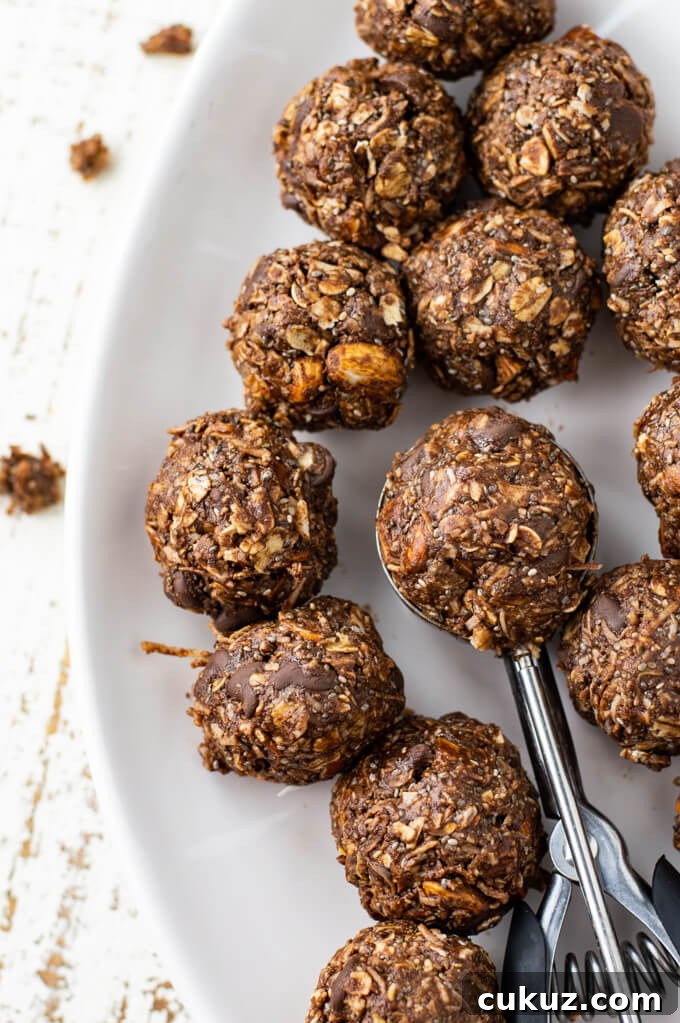 A white plate of Almond Joy Energy Balls with a cookie scoop in the middle.