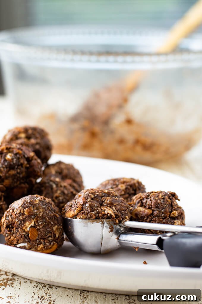 A white plate of Almond Joy Energy Balls with a cookie scoop in the middle.
