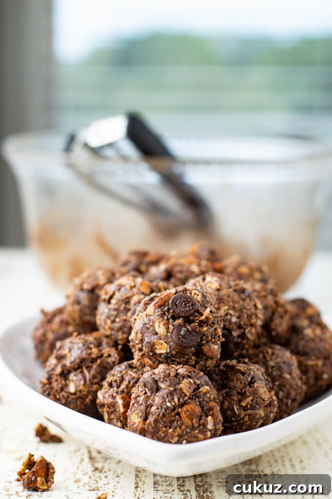 A white plate of Almond Joy Energy Balls sit in front of a blurred empty bowl of dough. 