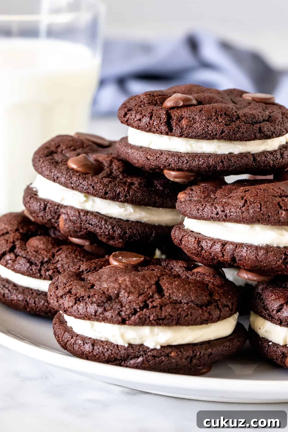 Plate of chocolate sandwich cookies with a glass of milk. 