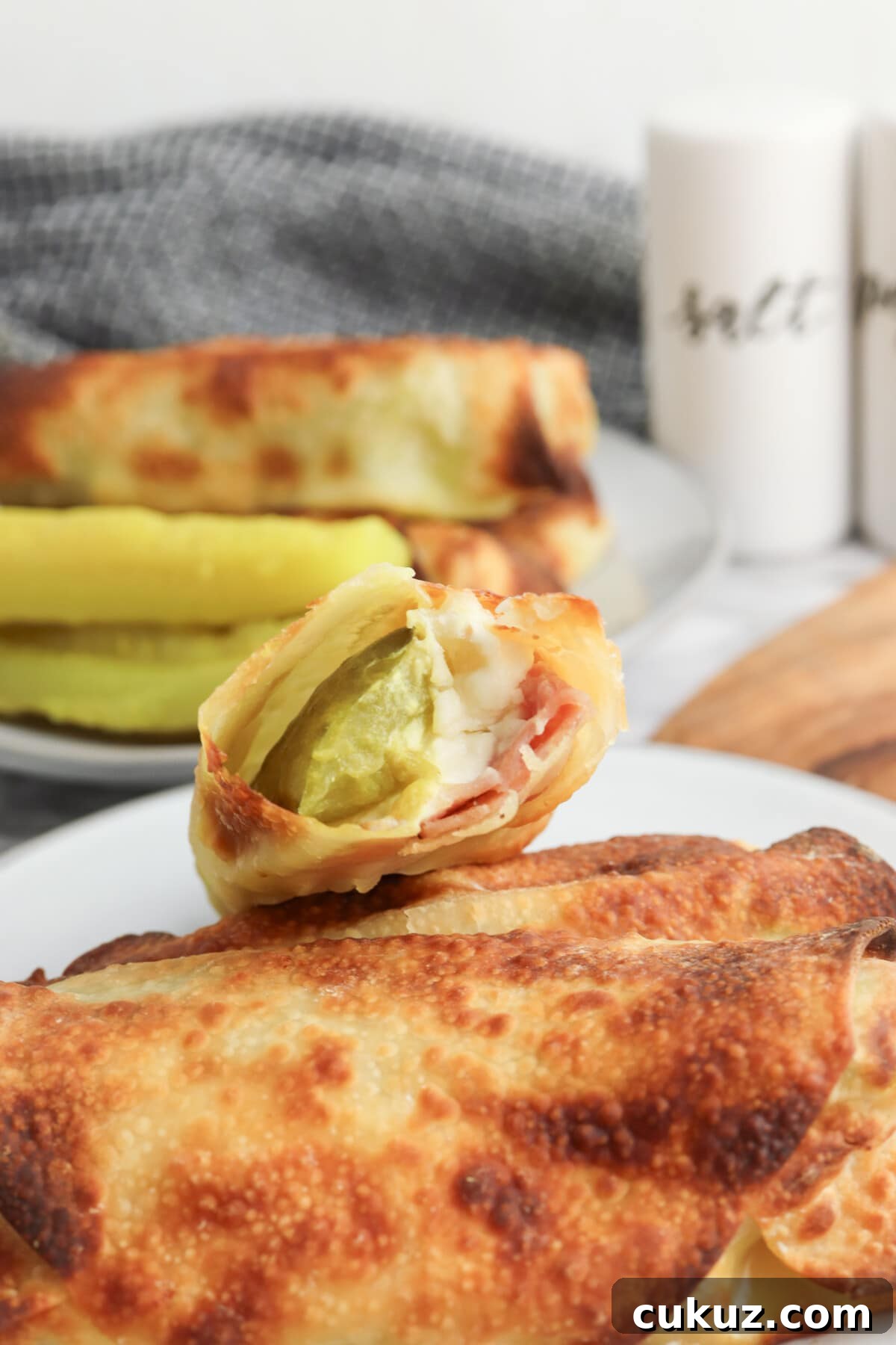 Try the delicious air fryer pickle egg rolls with ham and cream cheese pickle egg roll on a white plate