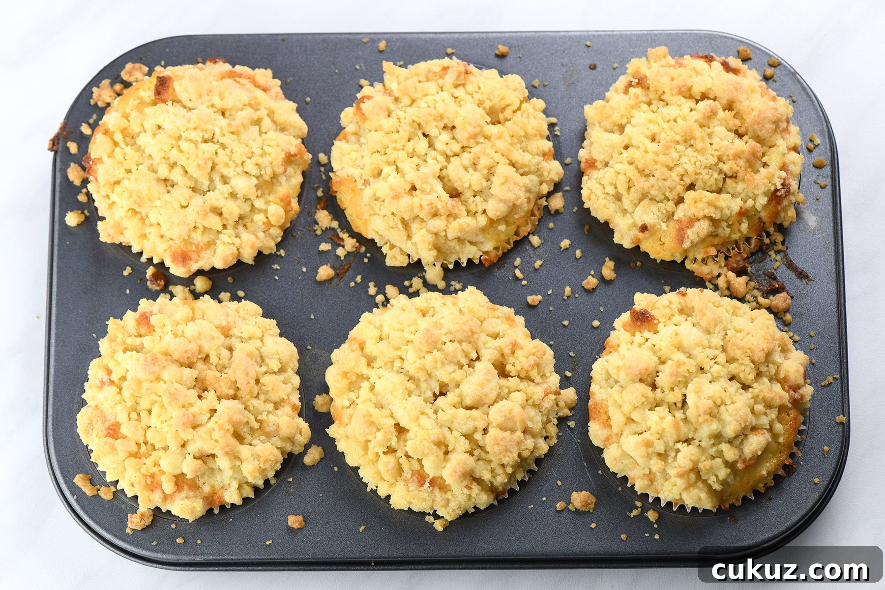 batch of lemon curd muffins with crumb topping baked in muffin pan