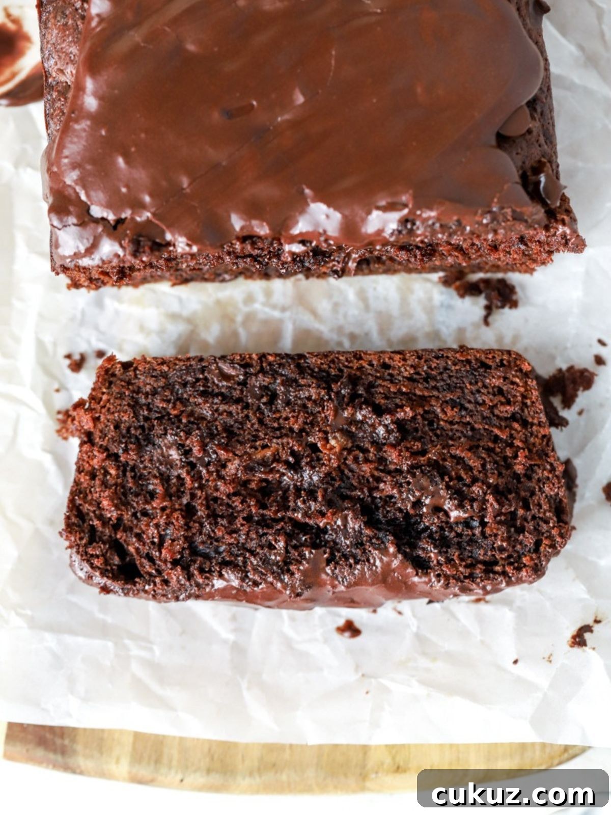 A slice of glazed chocolate loaf cake next to the loaf.