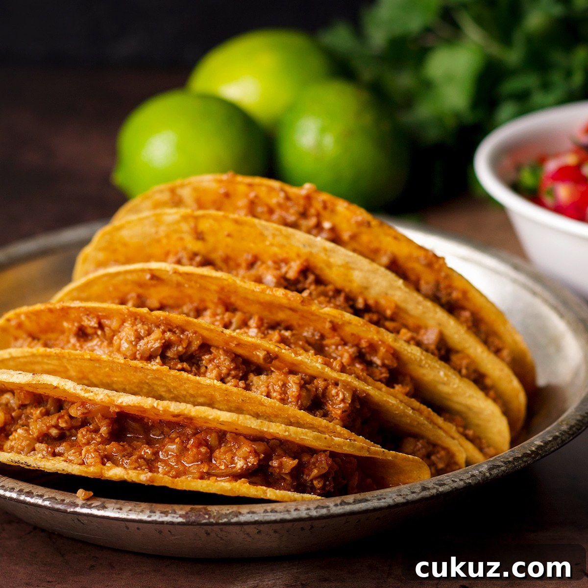 A tin plate filled with hard shell tacos stuffed with vegan taco meat.