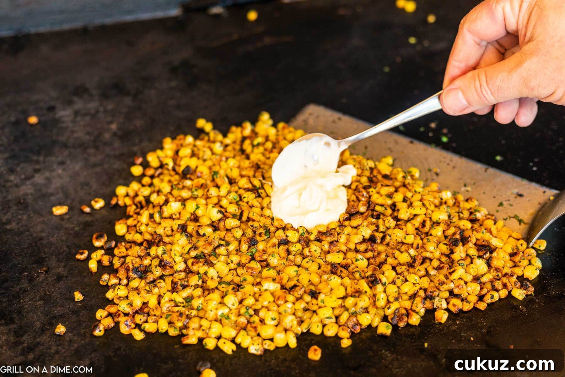 Topping corn with mayo on the griddle.