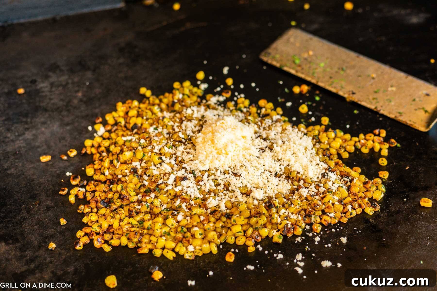 Topping corn with parmesan cheese on the griddle