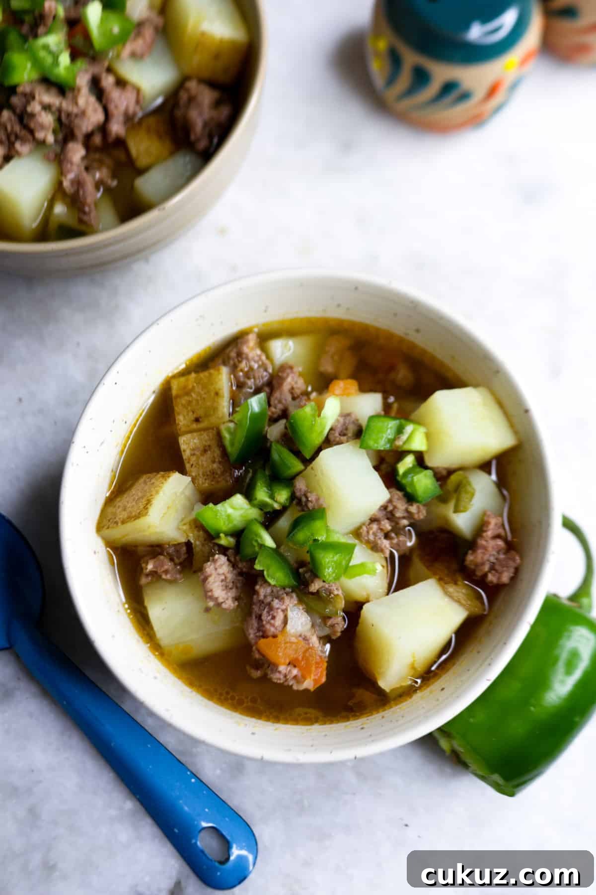 Caldillo de Carne Molida in a bowl with a jalapeño beside it
