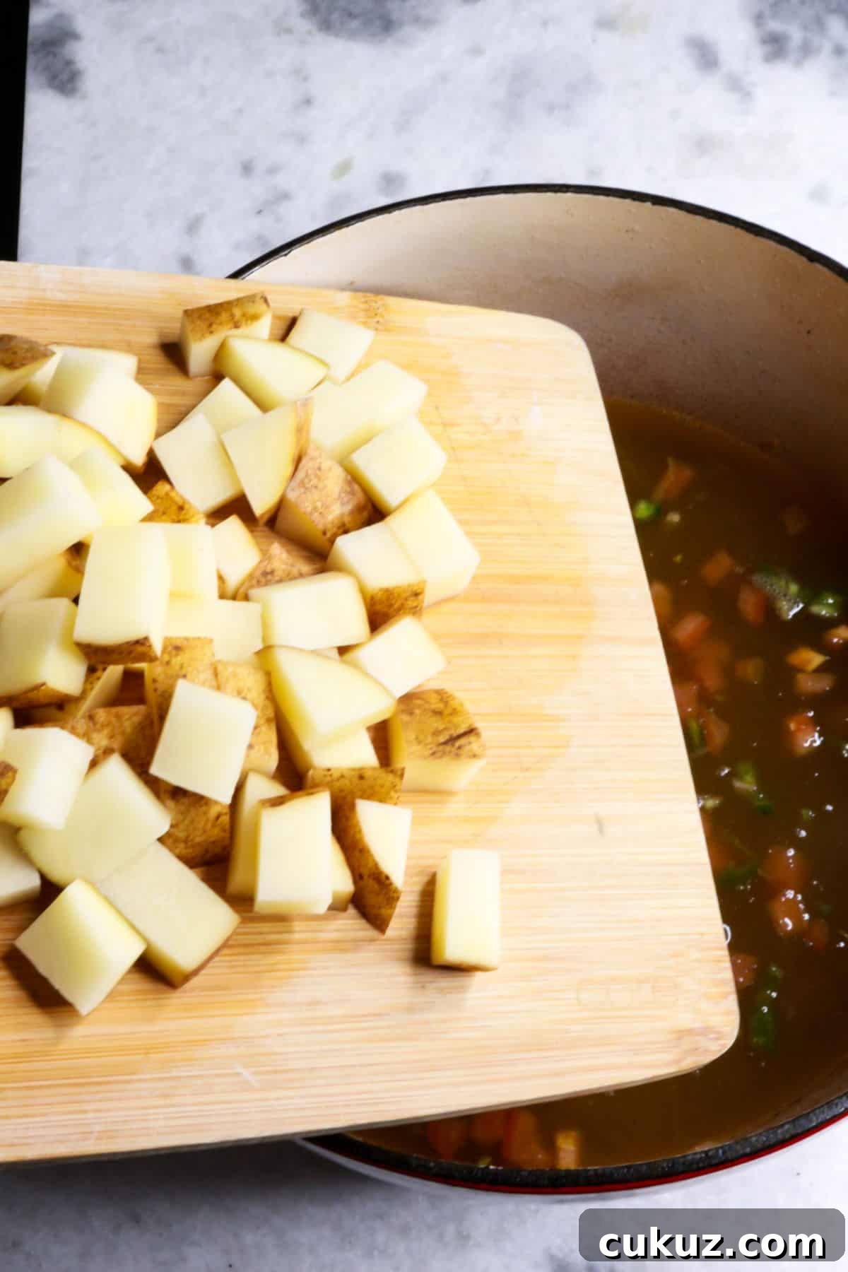 Adding potatoes to a pot of stew