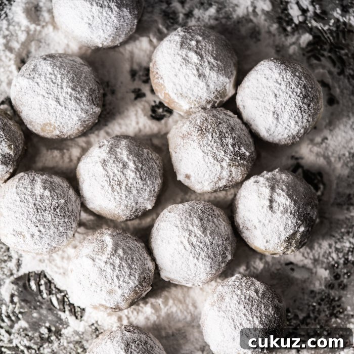 Rolling keto snowball cookies in powdered sweetener