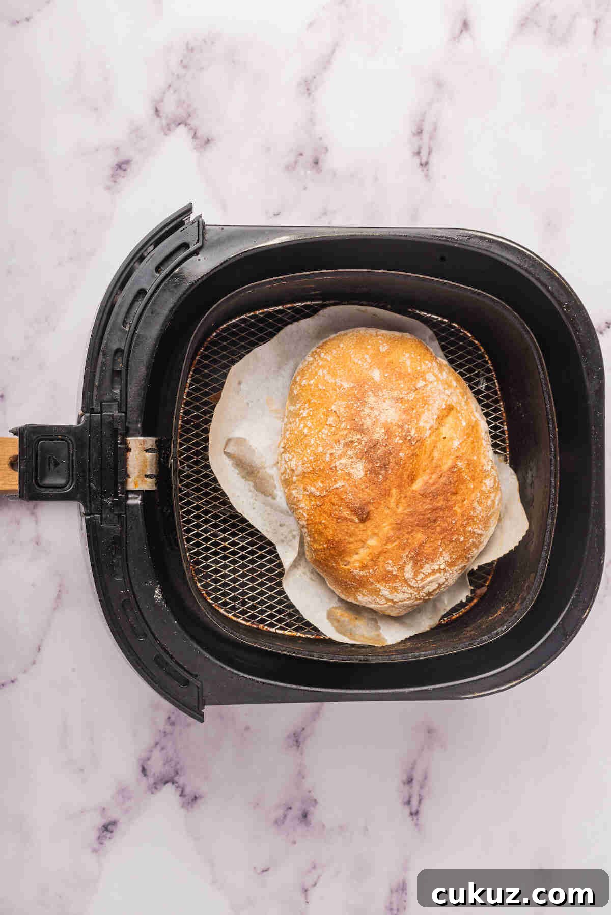 the baked bread loaf inside the air fryer basket.