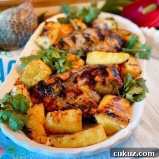 Platter filled with grilled jerk chicken breasts, grilled pineapple spears, and cilantro.