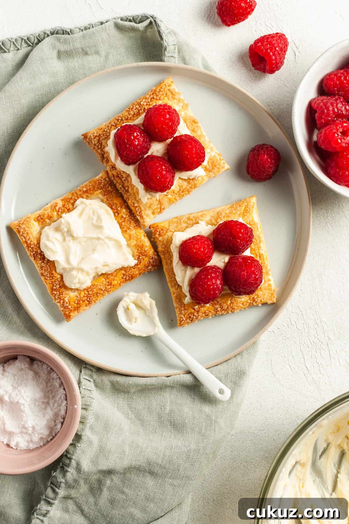 three tarts sitting on round plate, one with just cream cheese and the others with berries.