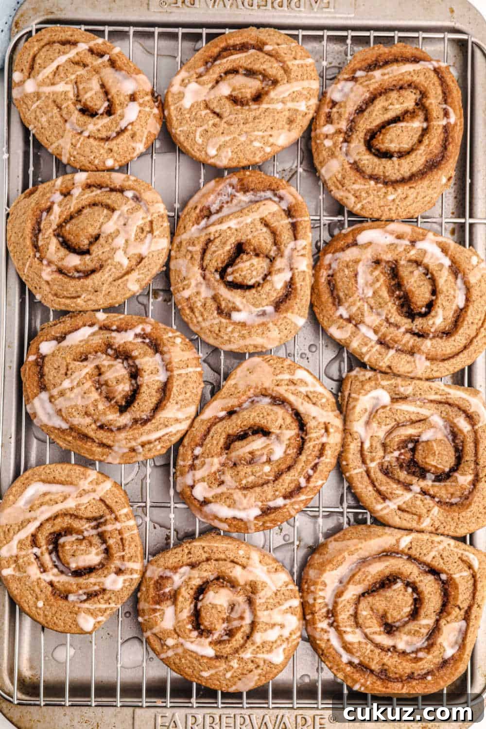 Cinnamon roll cookies on a wire rack on a baking tray
