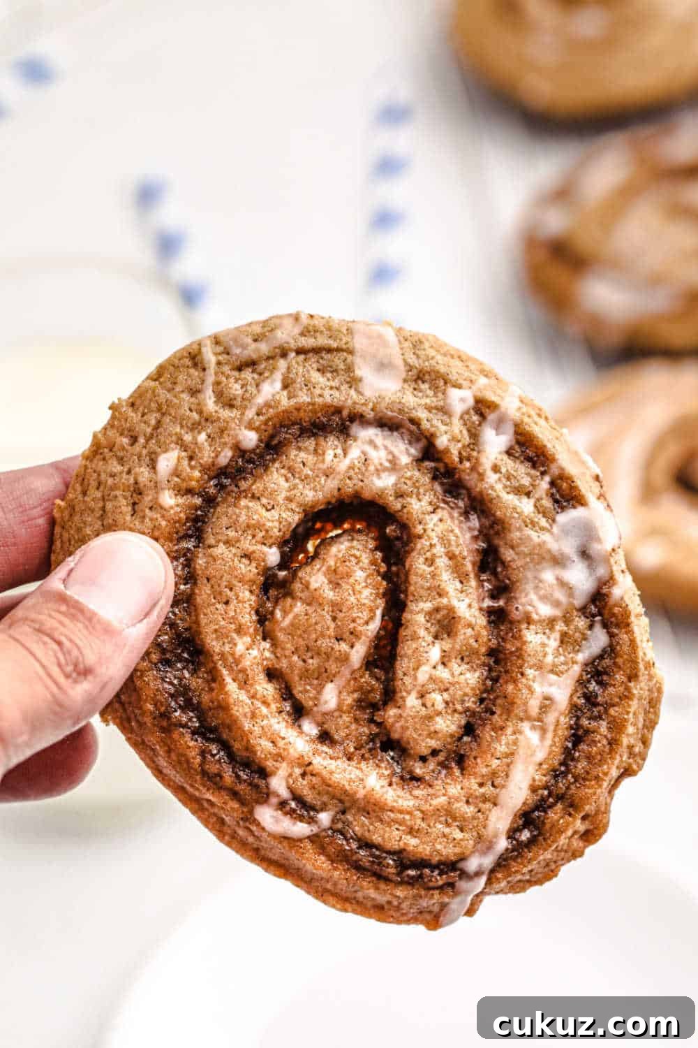 fingers holding a cinnamon roll cookie