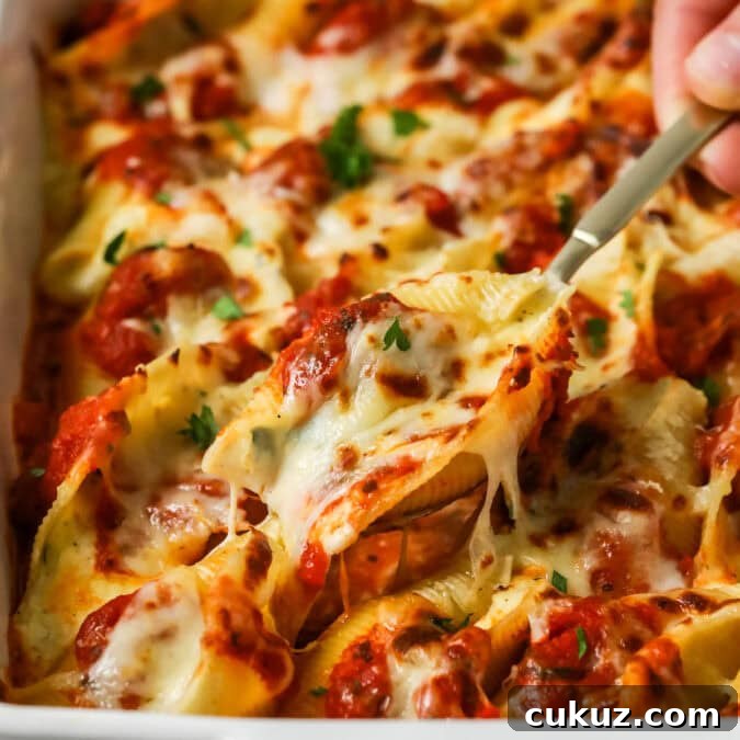 Spoon lifting a serving from a pan of stuffed shells.