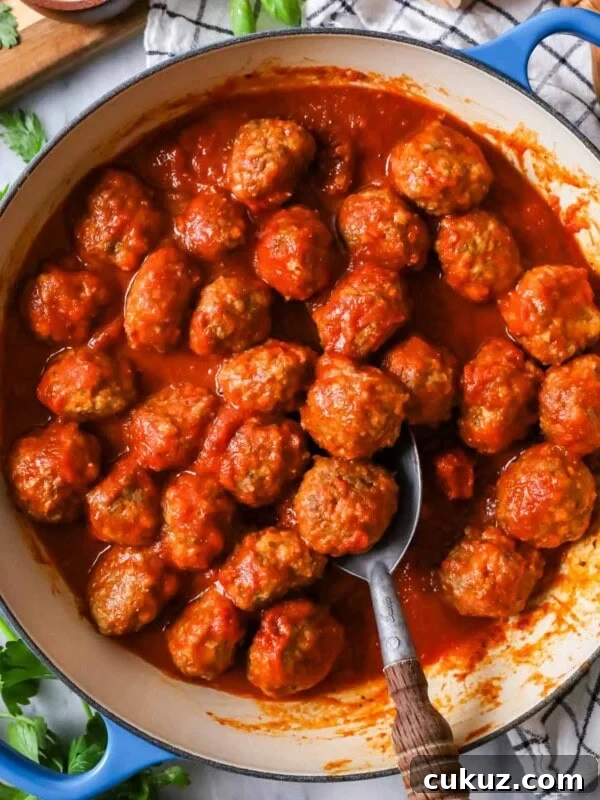 Overhead view of meatballs and tomato sauce in a skillet.