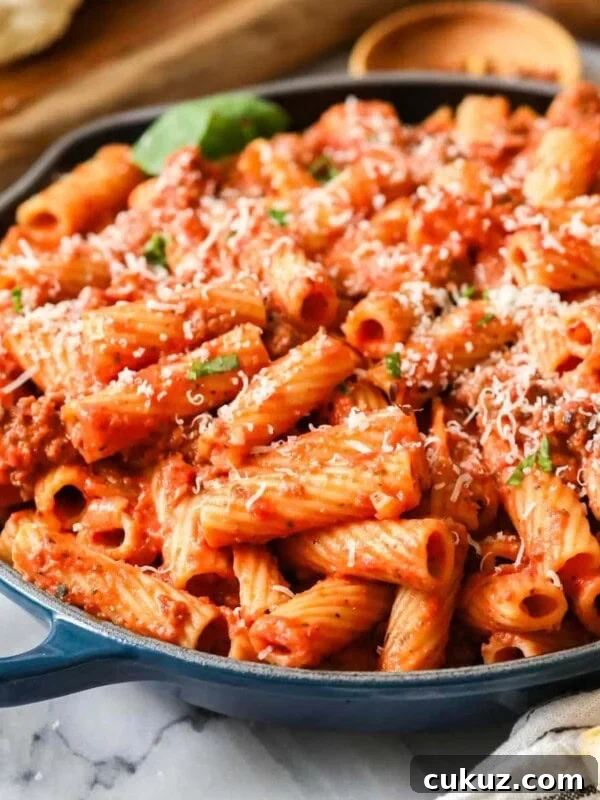 Skillet of homemade rigatoni topped with freshly grated parmesan cheese.