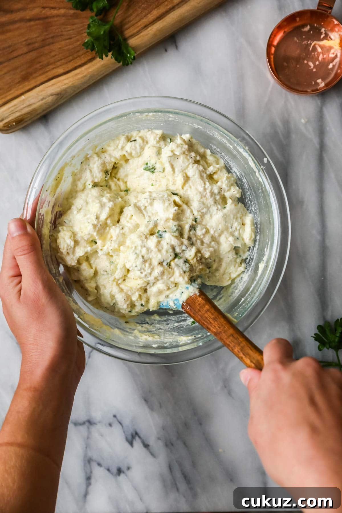 Overhead view of a cheese and herb pastsa filling being stirred together.