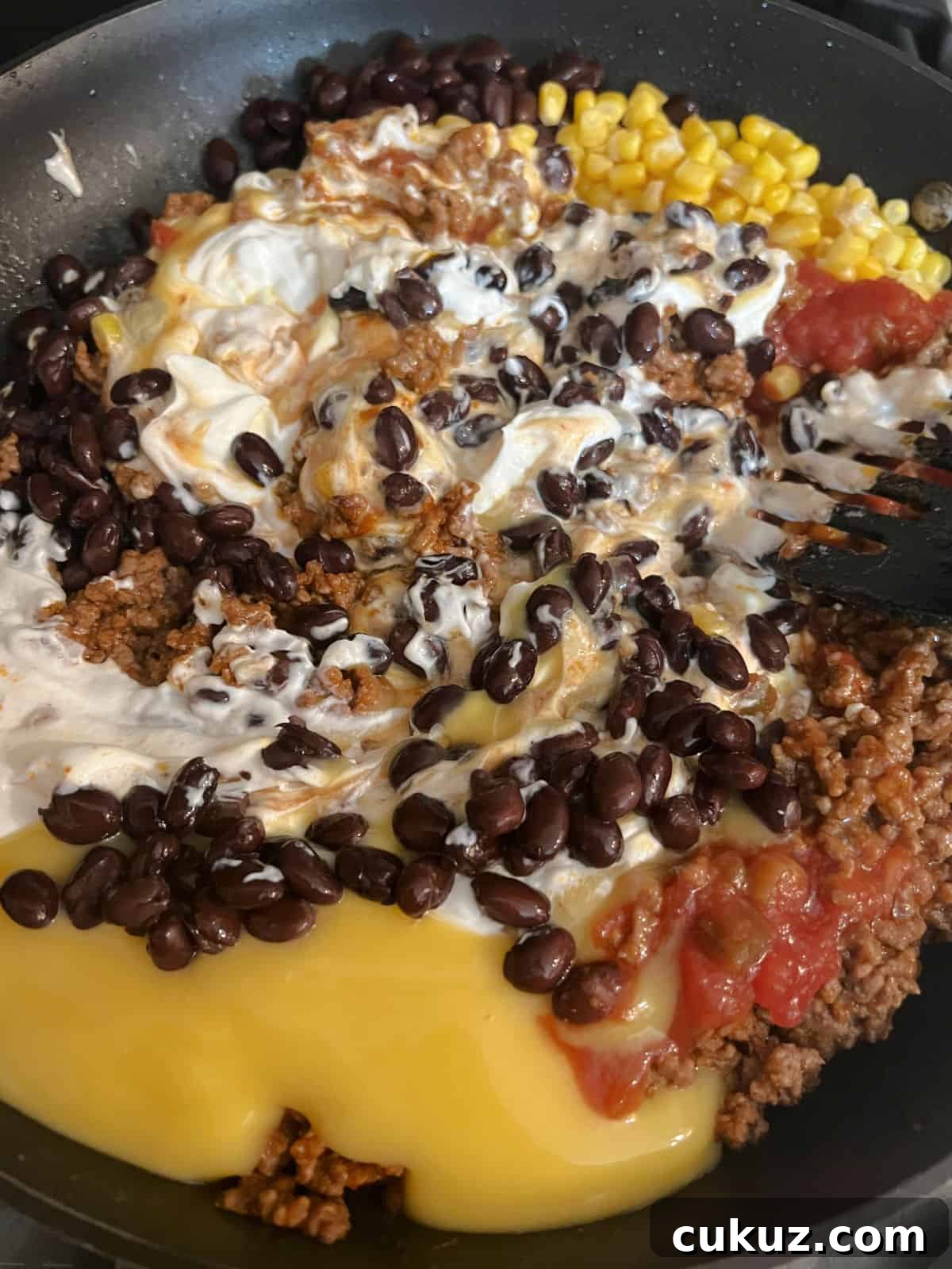 beans, meat, and other ingredients mixing in the skillet.