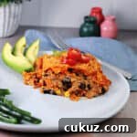 a serving of Doritos casserole made with ground beef, on a plate with avocado.