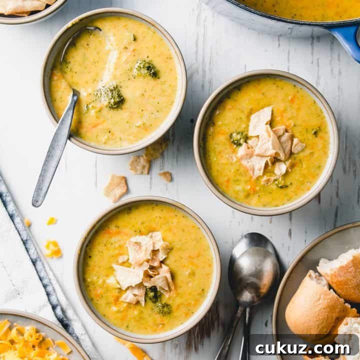 Three bowls of gluten free broccoli cheddar soup. Blue pot in background.