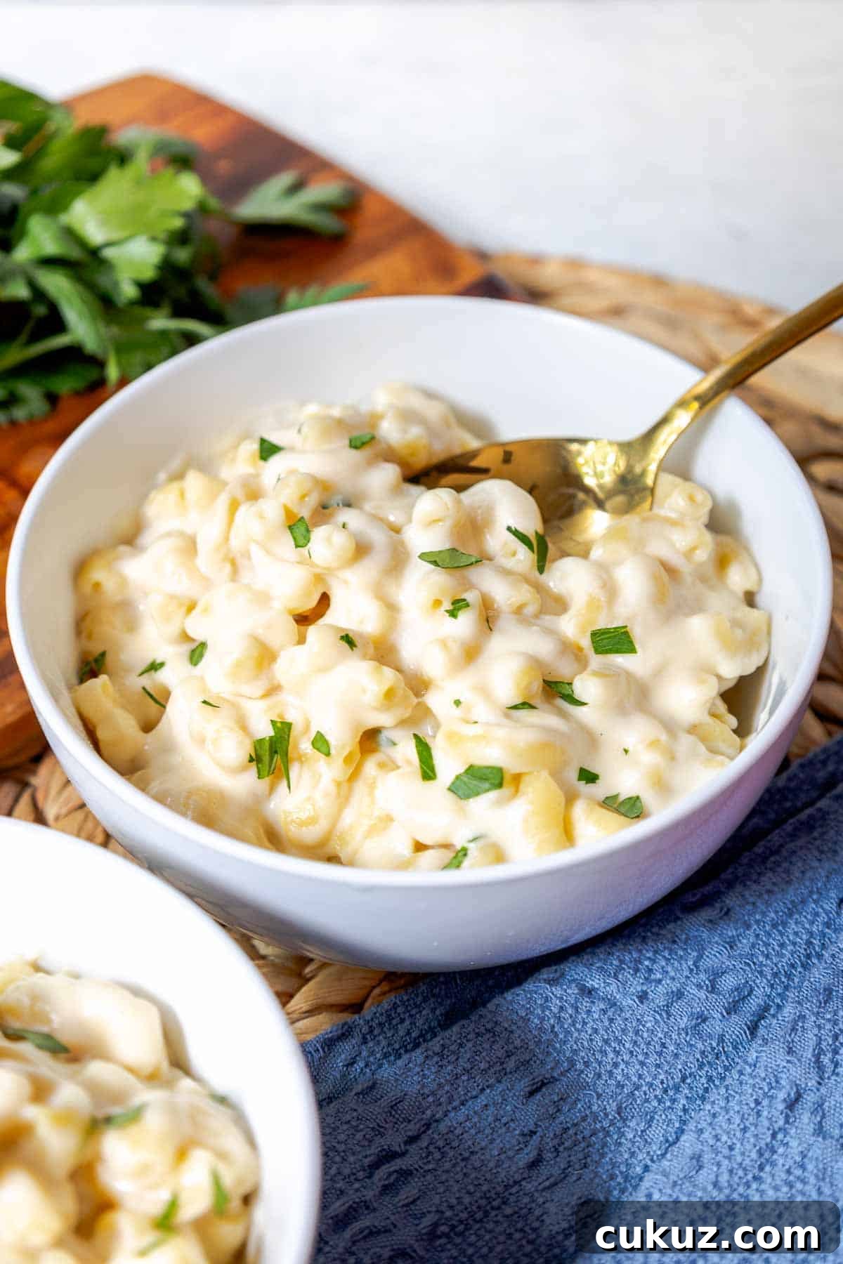 A bowl of creamy white cheddar mac and cheese topped with chopped parsley.