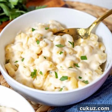 A bowl of creamy white cheddar mac and cheese topped with chopped parsley.