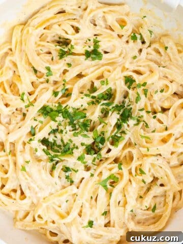 Cajun fettuccine Alfredo in a large skillet garnished with fresh parsley.