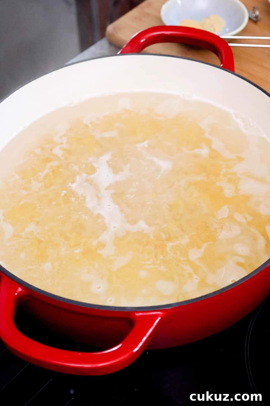 Elbow macaroni boiling in a large pot.