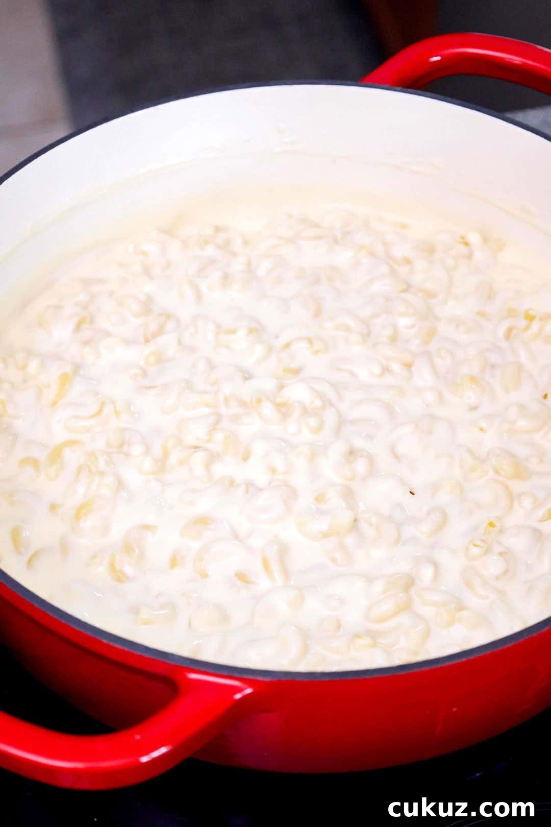 Cooked elbow macaroni in a large pot coated with cheese sauce.
