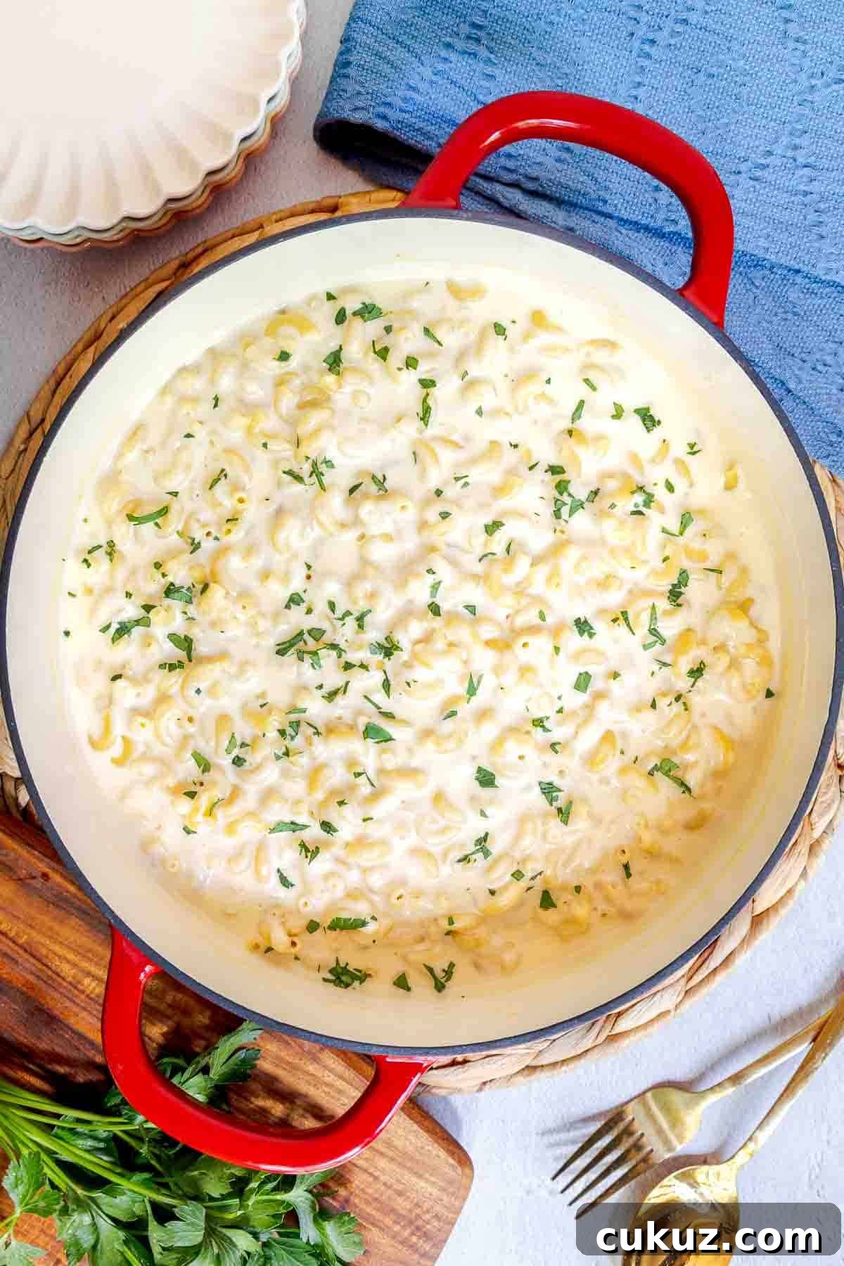 A pot of white cheddar mac and cheese topped with chopped parsley.