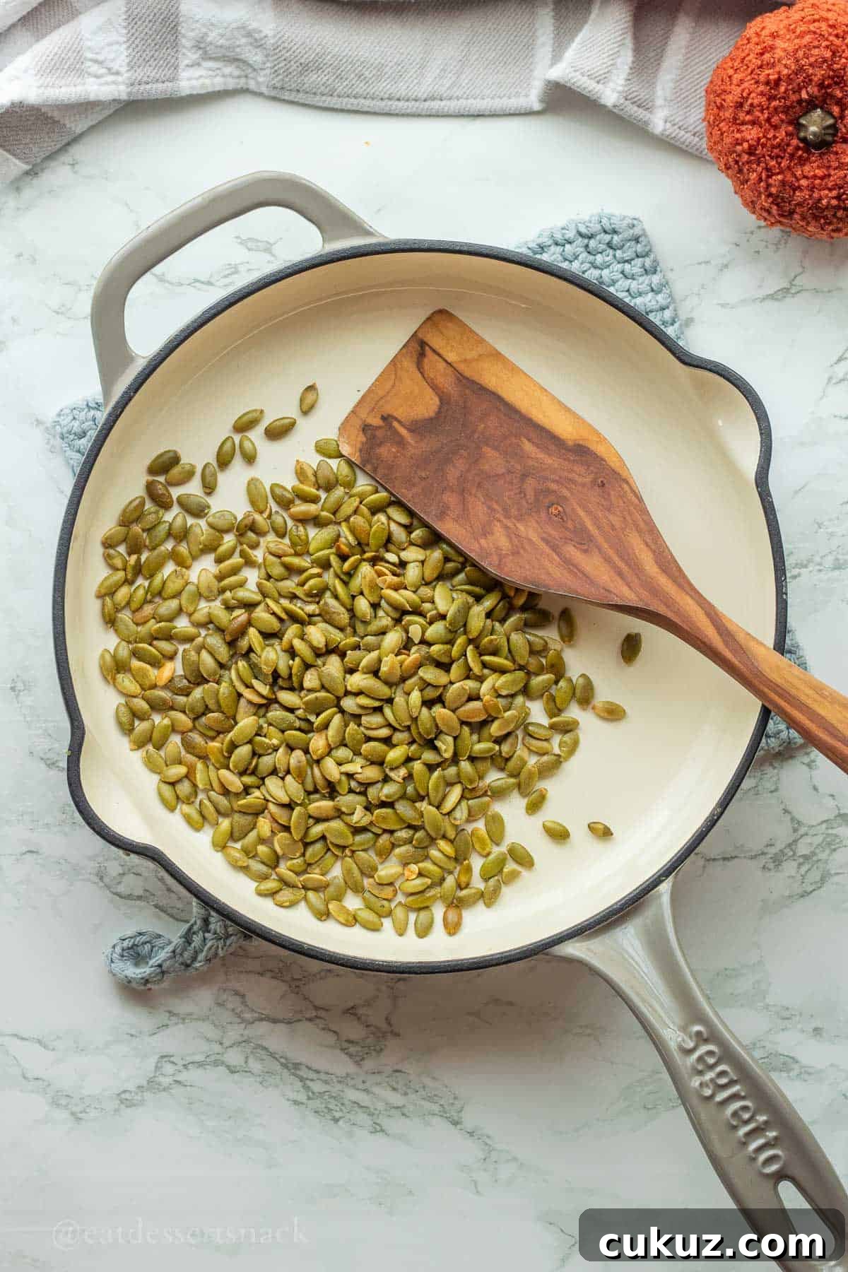 Roasting pepitas in pan with spatula.