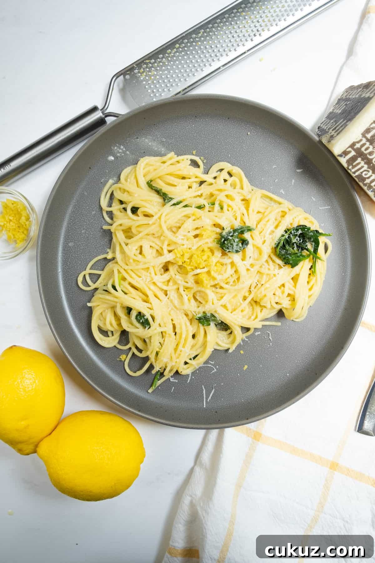 Lemon spinach pasta with lemons, zest and pecorino on side.